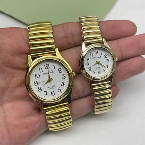 Detail view of gold quartz watches with elastic metal bands and white Arabic numeral dials