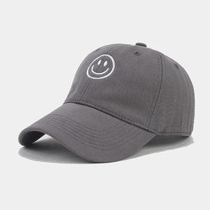 Detailed close-up of the white smiley face embroidery on the dark grey baseball cap