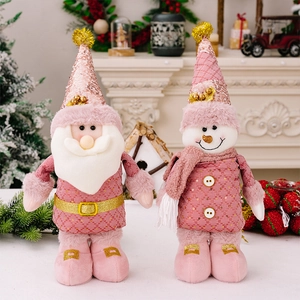 Close-up of pink Christmas Santa and Snowman plush dolls with gold sequins and soft fabric