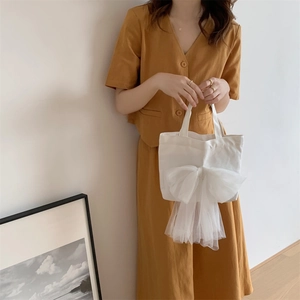 Detailansicht der weißen Segeltuchtasche mit großer Netzschleife zum gelben Outfit