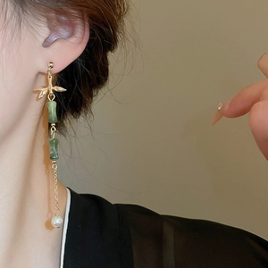 Detail of long tassel earrings with green bamboo beads and pearls on a model side profile