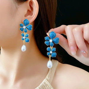 Macro shot of vintage blue enamel flower earrings with pearl drops in gold finish
