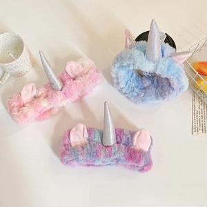 Detailed view of plush unicorn headbands with sequin horns in pink, blue, and violet hues
