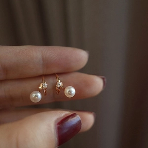 Close-up of double layer pearl earrings in rose gold with shimmering zircon accents