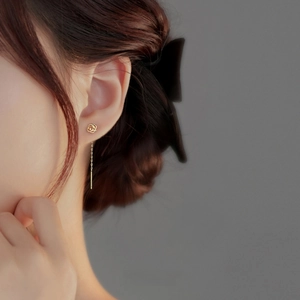 Elegant S999 sterling silver gold rose tassel earrings worn by a model on a dark background