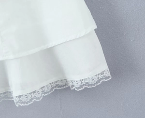 Close-up of the delicate white lace hem and fabric texture of the sleeveless dress