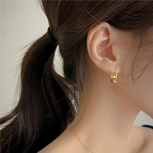 Close-up of a minimalist small gold hoop earring worn by a model for a stylish look