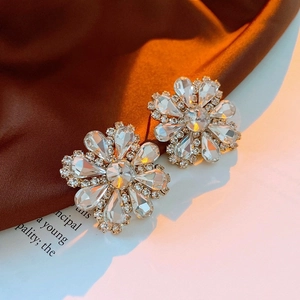 Macro detail of French flower stud earrings featuring crystal petals and a sparkling center