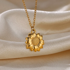 Detail of a golden sunflower pendant necklace on elegant beige silk fabric background