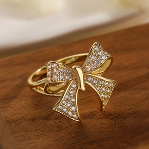 Exquisite 18K gold plated bow ring with pavé zircons on a dark wooden base
