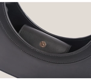 Close-up of black leather bag interior showing premium texture and gold metal snap button