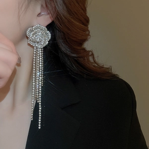 Detailed close-up of silver tassel earrings with diamond floral accents worn by a model
