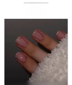 Close-up of French tip press-on nails with silver glitter and nude pink short square shape