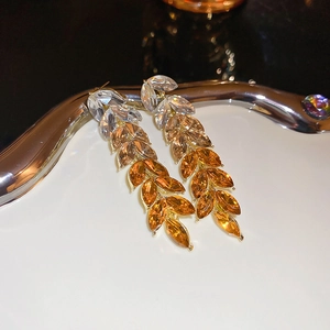 Detail of leaf-shaped tassel earrings with amber gradient crystals in a gold setting