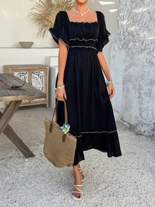 Detail view of smocked elastic waist and ruffled cuffs on black Bohemian dress