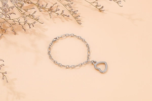 Detailed macro view of the silver chain bracelet featuring a textured hollow heart charm