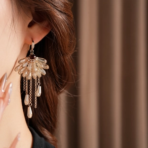 Macro view of gold tassel earrings with amber fan-shaped crystal and zircon hanging detail