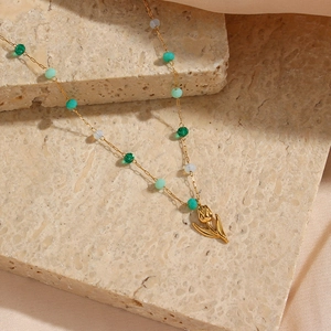 Détail du collier pendentif tulipe avec perles colorées sur support en pierre