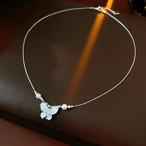 Detailed close-up of a silver butterfly pendant necklace with elegant pearl accents