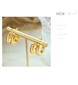 Macro detail of glossy golden double C-shaped earrings on a premium metal jewelry stand