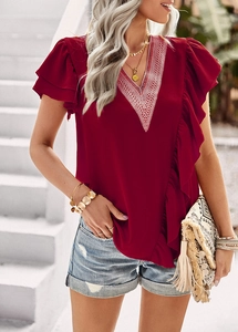 Close-up of red V-neck short sleeve top with white embroidery and ruffled sleeve details