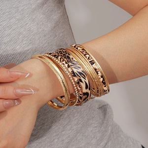 Detail of stacked gold metal bangles featuring leopard print leather and crystal accents