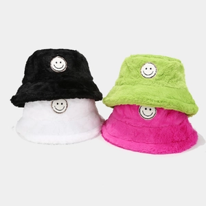 Detail of plush bucket hats in multiple colors featuring a stitched smiley face patch