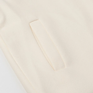 Detailed close-up of side pocket and wool texture on cream white winter coat