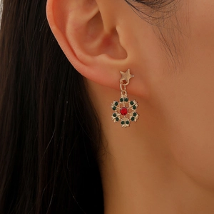Detailed view of Christmas star snowflake earrings with red and green gems worn on ear