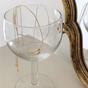 Artistic display of gold and silver teardrop pendant necklaces on a vintage mirror