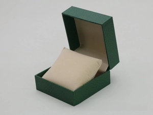 Detailed view of dark green leather texture watch box with a beige soft cushion pillow