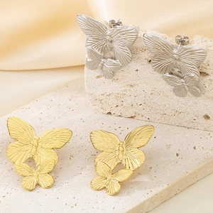 Macro shot of gold and silver double butterfly earrings on a textured stone display