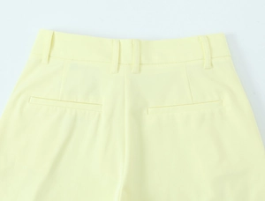 Detail der gelben High-Waist-Hose mit Gürtelschlaufen und dekorativen Gesäßtaschen