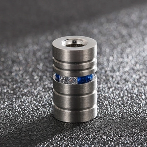 Macro shot of brushed stainless steel dumbbell charm with blue and clear gemstones