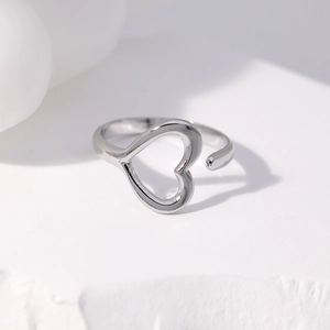 Detailed view of silver heart-shaped open ring on a textured white stone surface