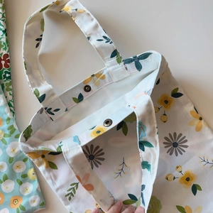 Macro detail of floral canvas tote bag featuring metal snap button and interior lining