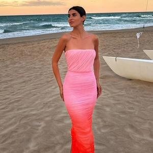 Details eines eleganten Netz-Trägerkleids mit Rosa-Orange-Verlauf am Strand