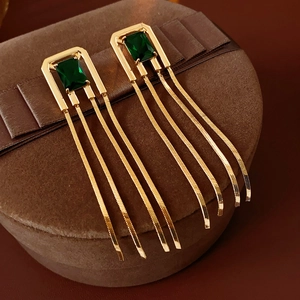 Detail of vintage gold earrings with emerald green zircon and long tassel on velvet box