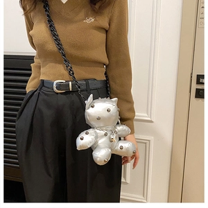 Detail view of a silver bear-shaped crossbody bag with stud accents and black chain strap