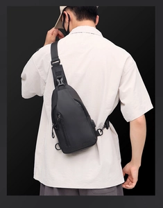 Close-up of black men's chest bag featuring external USB charging port and adjustable strap