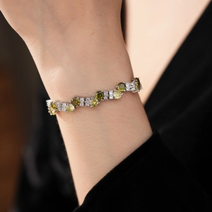 Close-up of zircon tennis bracelet with green and white round-cut stones on wrist