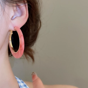 Detailed view of pink marble pattern C-shaped hoop earring on model with golden inner rim