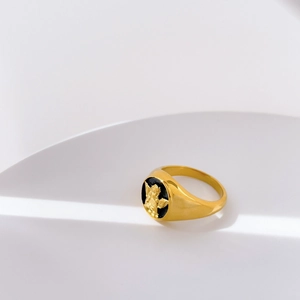 Macro detail of gold signet ring with black oval face and angel relief engraving