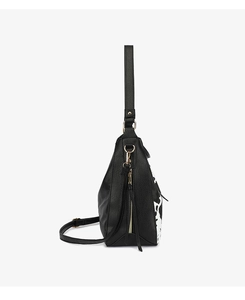 Detail view of a black faux leather tote with cow print panel and gold hardware