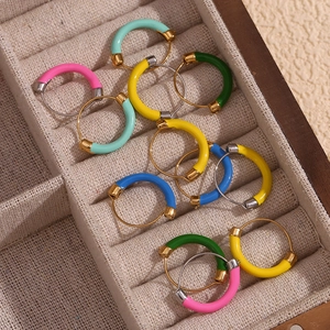 Detail of colorful enamel drip earrings in a beige jewelry box with a gold finish