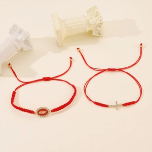Detail of red braided bracelets with gold Virgin Mary medal and rhinestone cross charms
