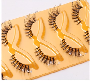 Close-up of 5 pairs cat-eye false eyelashes with pearls on yellow tray