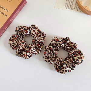 Detail of two leopard print satin scrunchies with elegant silk texture on white background