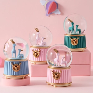 Detailed view of four colorful crystal snow globes with deer figurines and music box base