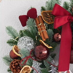 Classic Christmas wreath with red velvet bow, pine cones and decorative balls on grey wall